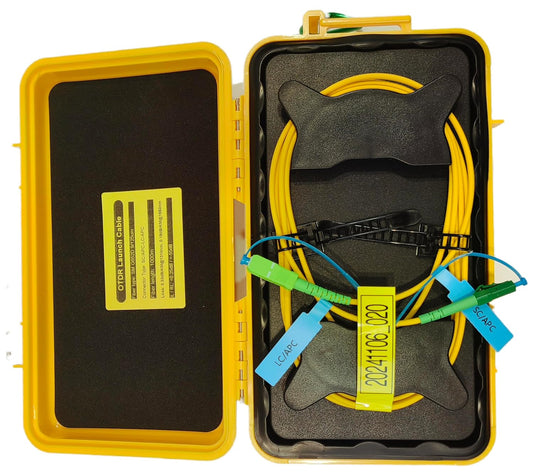 The FIBAsource OTDR Launch Cable, a product from FIBAsource Ltd, is a yellow box crafted for telecom technicians containing a 1km single mode fiber optic extension cord with SC/APC and LC/APC connectors. A tag reading 20244166J20 is attached. Inside, black padding offers labels and compartments crucial for accurate network testing during OTDR procedures.