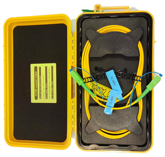 A yellow plastic case contains the FIBAsource OTDR Launch Cable 2km SC/APC to SC/UPC Single Mode Fibre Optic Extension Cord from FIBAsource Ltd, featuring green connectors designed for telecom technicians. The open case displays foam padding and labels inside the lid, making it ideal for fibre optic testing.